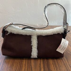 Small brown handbag with serpa trim adjustable strap.